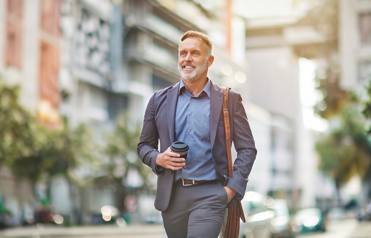 Muž kráčajúci v obleku s kávou